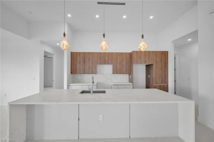 Kitchen with modern cabinets, light stone countertops, tasteful backsplash, and wood finish cabinetry