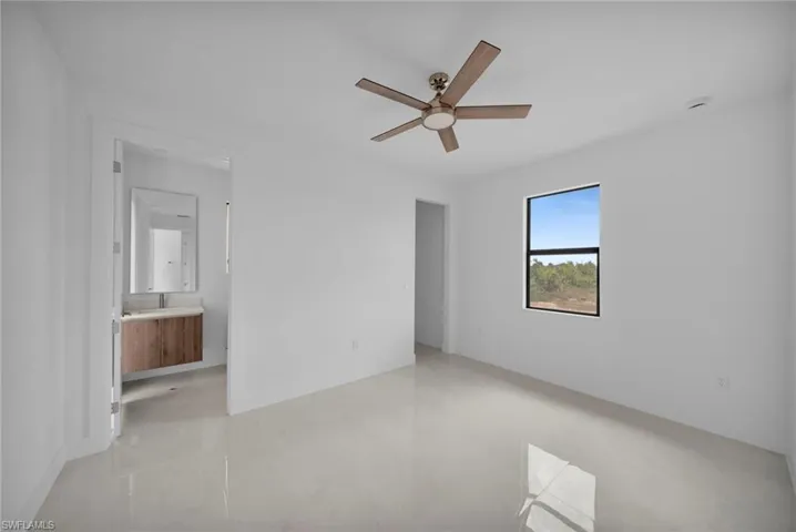 Unfurnished bedroom featuring finished concrete floors, ceiling fan, and ensuite bathroom