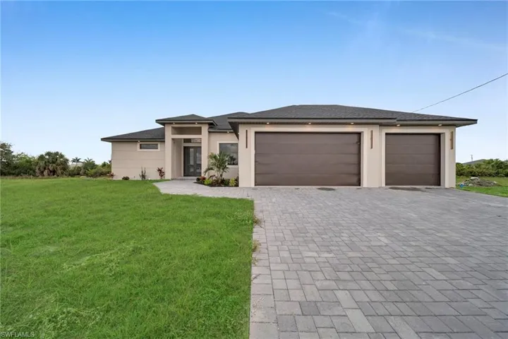 Prairie-style home with a front yard, decorative driveway, a garage, roof with shingles, and stucco siding