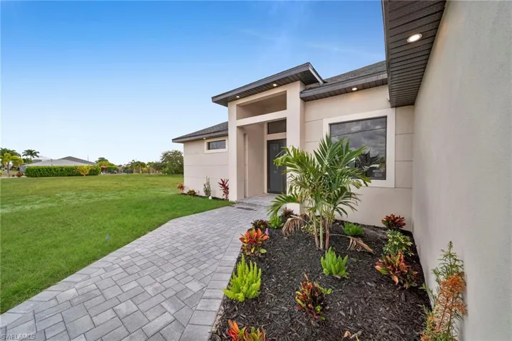 Doorway to property with a lawn and stucco siding