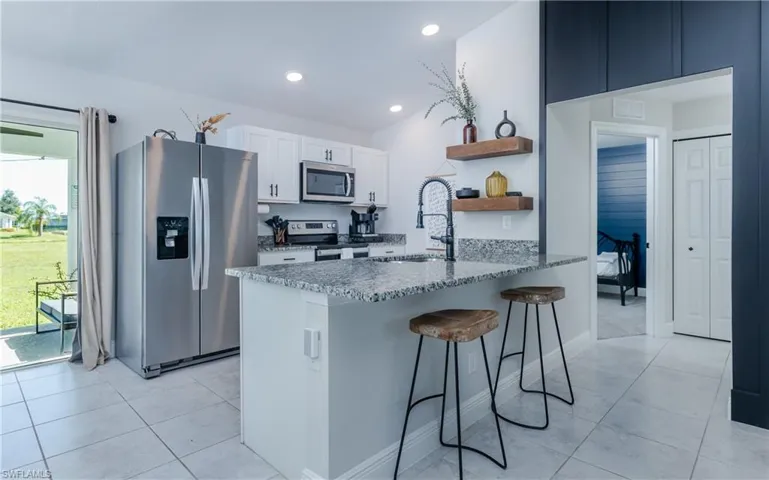 Kitchen with white cabinets, appliances with stainless steel finishes, sink, and light tile floors