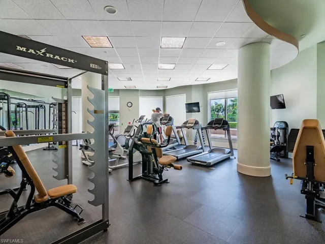 Exercise room with ornate columns and a drop ceiling