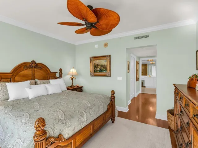 Bedroom with hardwood / wood-style flooring, crown molding, and ceiling fan