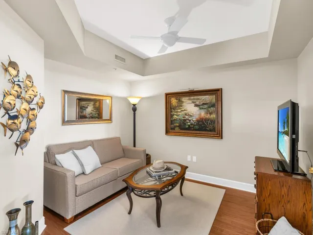 Living room with hardwood / wood-style flooring, ceiling fan, and a raised ceiling