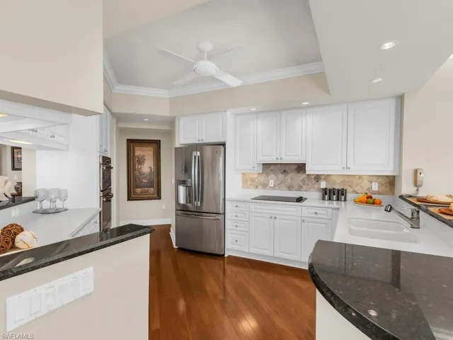 Kitchen with white cabinetry, sink, ornamental molding, and stainless steel appliances