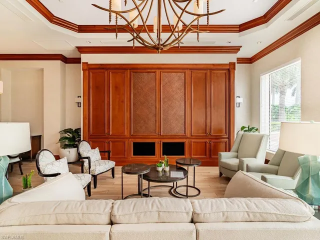 Living room featuring an inviting chandelier, a tray ceiling, ornamental molding, and light hardwood / wood-style floors