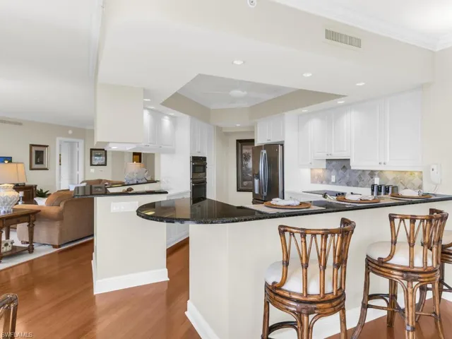 Kitchen with white cabinets, hardwood / wood-style flooring, kitchen peninsula, stainless steel appliances, and crown molding