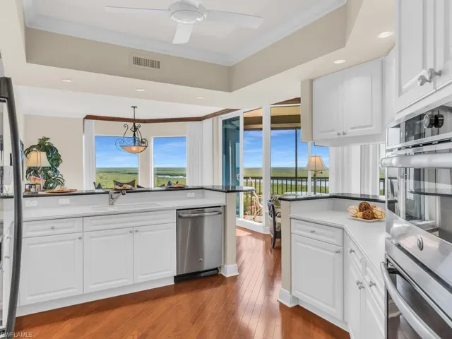 Kitchen with sink, white cabinetry, ornamental molding, kitchen peninsula, and stainless steel appliances