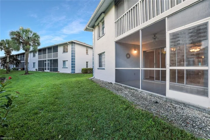 View of green lawn featuring a sunroom, a balcony, and ceiling fan