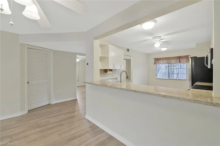 Kitchen featuring a ceiling fan, light wood finished floors, open shelves, and white cabinets