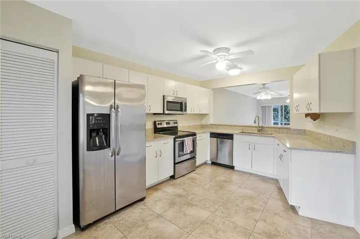 Kitchen with stainless steel appliances, white cabinets, a ceiling fan, and light tile patterned floors