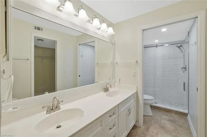 Bathroom featuring double vanity, a shower stall, light tile patterned floors, a walk in closet, and recessed lighting