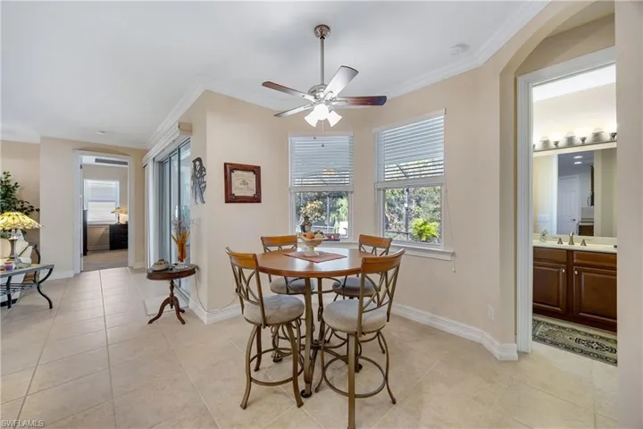 Tiled dining space featuring crown molding, sink, and ceiling fan