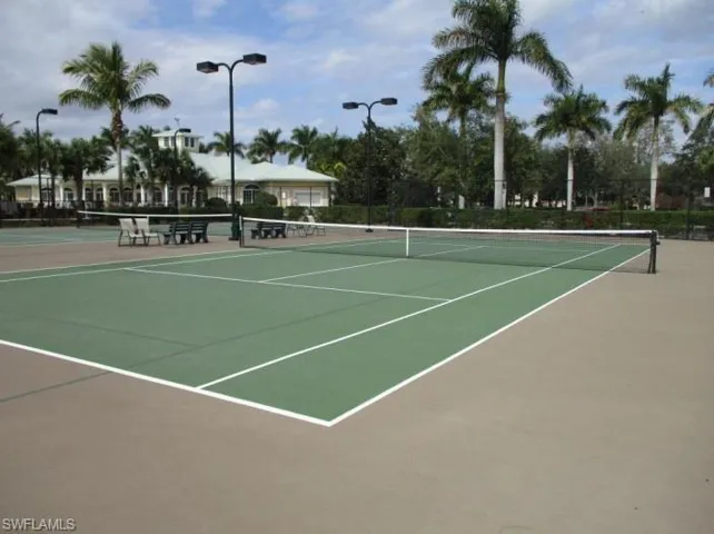 View of community tennis court featuring basketball hoop