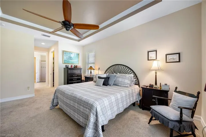 Carpeted bedroom featuring a tray ceiling and ceiling fan
