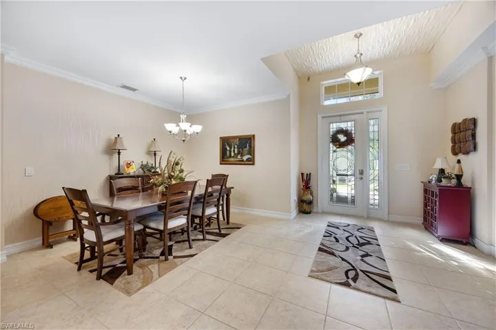 Tiled dining area with an inviting chandelier and crown molding