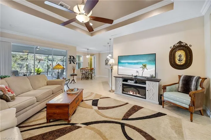 Living room with a tray ceiling, ceiling fan, and crown molding