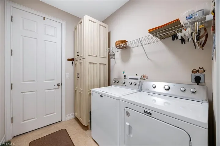 Laundry room with cabinets, light tile patterned floors, and washing machine and clothes dryer