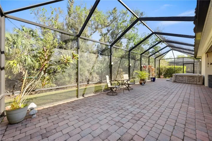 View of patio / terrace featuring a hot tub and a lanai
