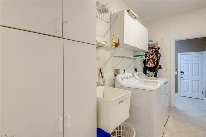 Washroom featuring cabinet space, separate washer and dryer, and light tile patterned floors