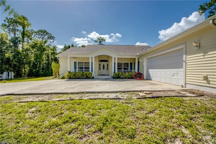 Ranch-style home featuring concrete driveway, an attached garage, a porch, and a front lawn