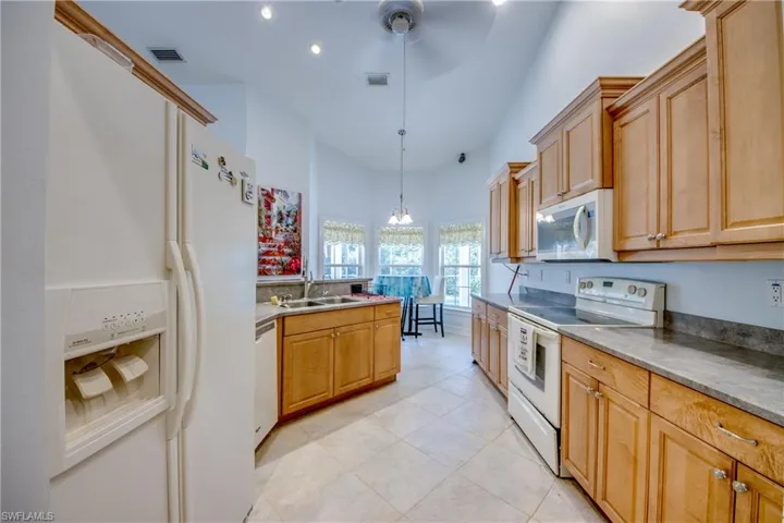 Kitchen featuring white appliances, light tile patterned flooring, recessed lighting, hanging light fixtures, and ceiling fan