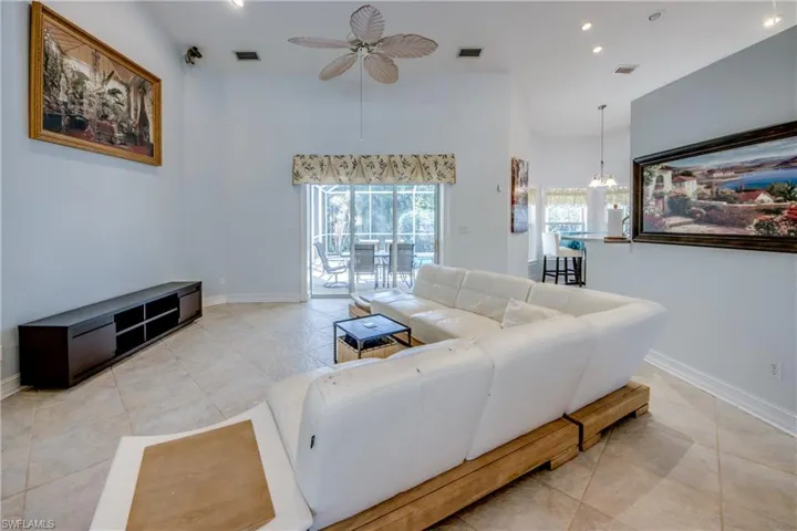 Living area with ceiling fan, high vaulted ceiling, a chandelier, tile patterned floors, and recessed lighting