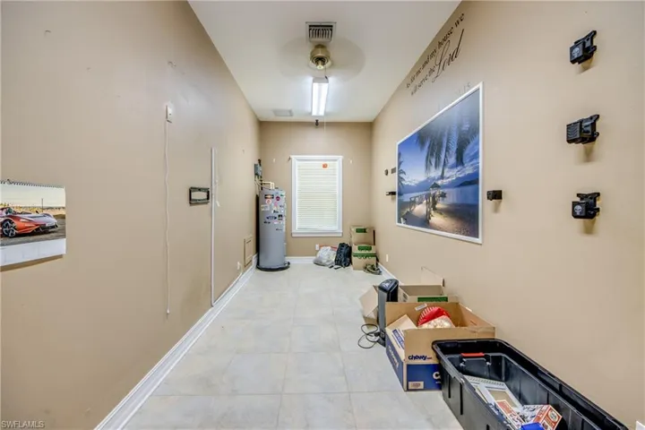 Corridor featuring water heater and light tile patterned floors