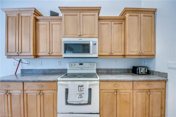Kitchen with white appliances, light brown cabinets, and dark countertops