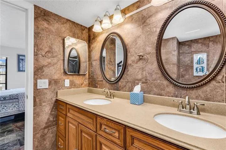 Primary ensuite bathroom with double vanity and sinks, and walk-in tiled shower