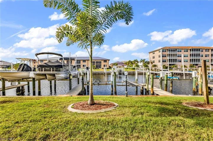 Dock area featuring boat lift, a lawn, and a water view