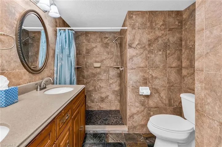 Primary ensuite bathroom with double vanity and sinks, and walk-in tiled shower