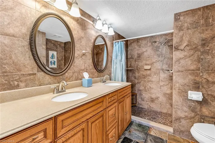 Primary ensuite full bathroom with double vanity and sinks, and walk-in tiled shower