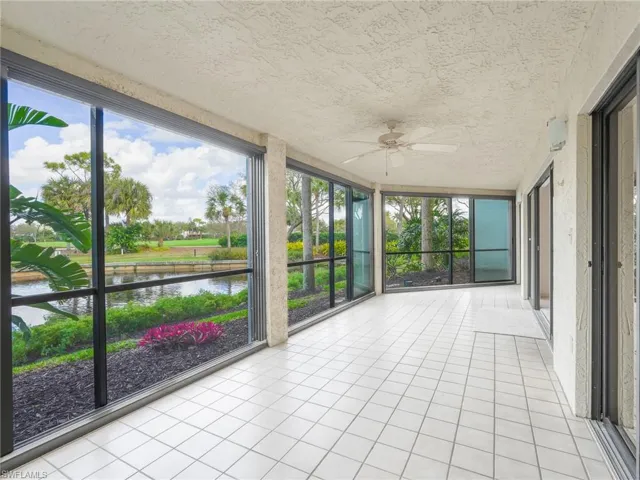 Unfurnished sunroom featuring a ceiling fan and a water view