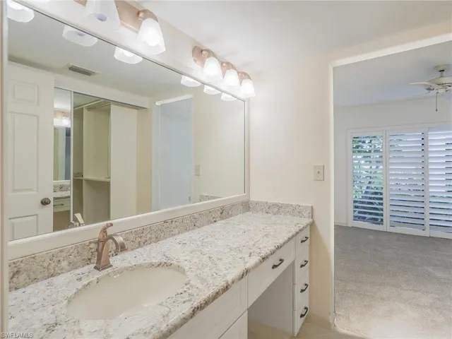 Bathroom featuring vanity, light colored carpet, and ceiling fan