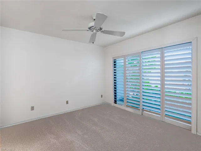 Carpeted empty room with ceiling fan and baseboards