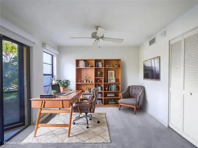 Home office/bedroom featuring light colored carpet and ceiling fan