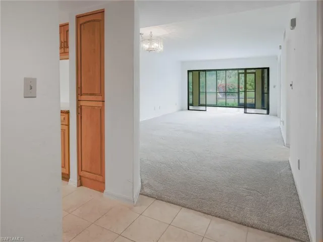 Empty room featuring a chandelier and light colored carpet