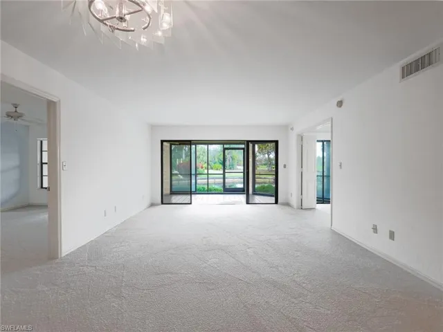 Unfurnished Living room with light carpet, ceiling fan, and hanging lights