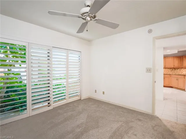 Empty room featuring light carpet, ceiling fan, and light tile patterned flooring