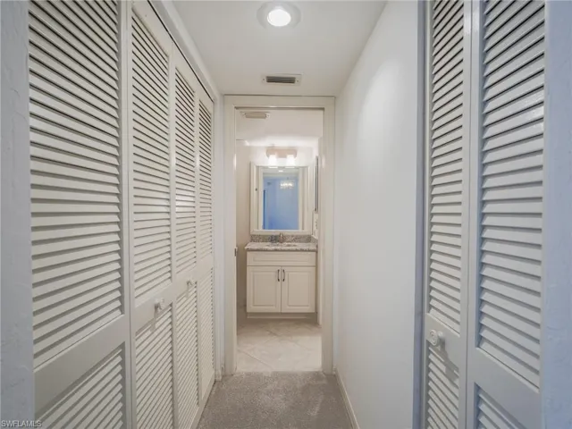 Corridor featuring a sink and light carpet