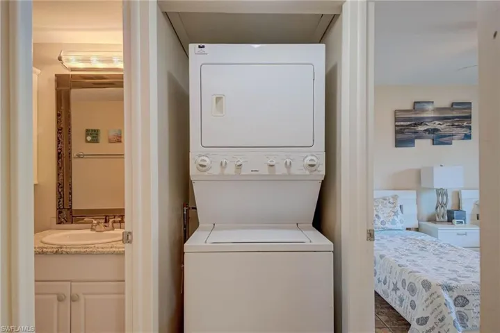 Laundry room with stacked washing machine and dryer and tile patterned floors