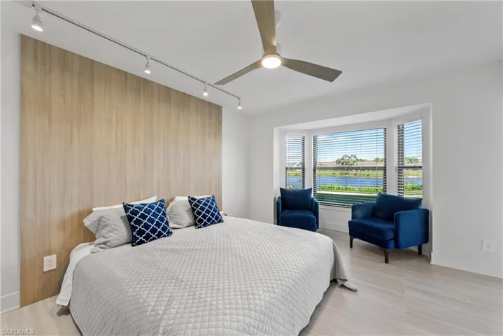 Bedroom with track lighting, a ceiling fan, an accent wall, and wood walls