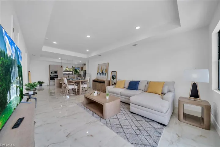 Open-concept living space featuring high ceilings, recessed lighting, and large format tile flooring