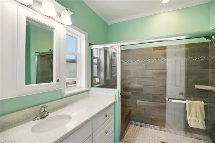 Bathroom featuring vanity, a stall shower, and crown molding