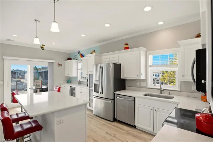 Kitchen featuring white cabinets, healthy amount of natural light, stainless steel appliances, recessed lighting, and ornamental molding