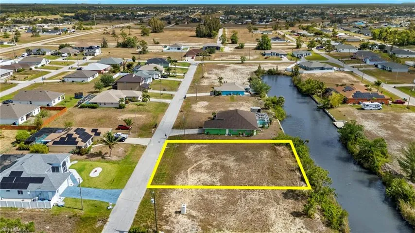 Aerial view of residential area featuring property boundaries highlighted and a nearby body of water