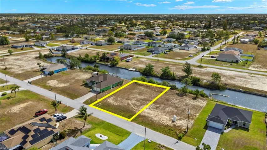 Aerial view of residential area with property boundaries highlighted and a nearby body of water