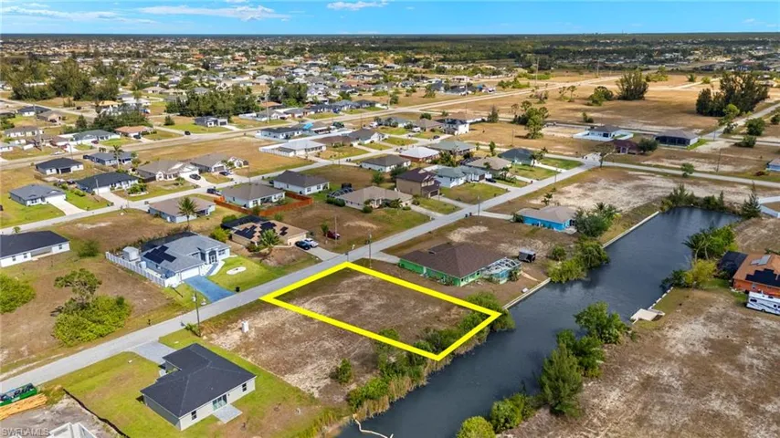 Aerial view of residential area featuring a nearby body of water and property parcel outlined