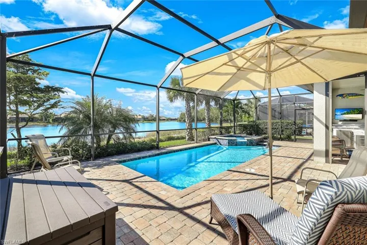 View of pool featuring a lanai, an in ground hot tub, a water view, and a patio
